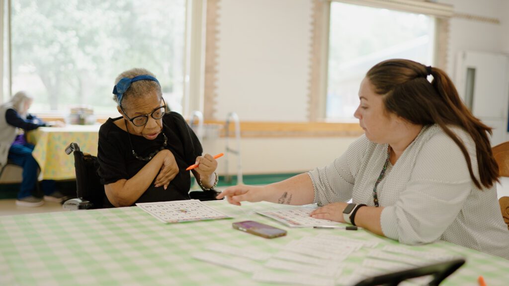 A woman is assisted by a nurse while doing a memory care therapy activity
