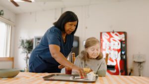 A nurse helps a woman during lunch at a skilled nursing facility